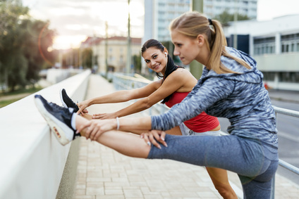 Two women stretching feet before jogging